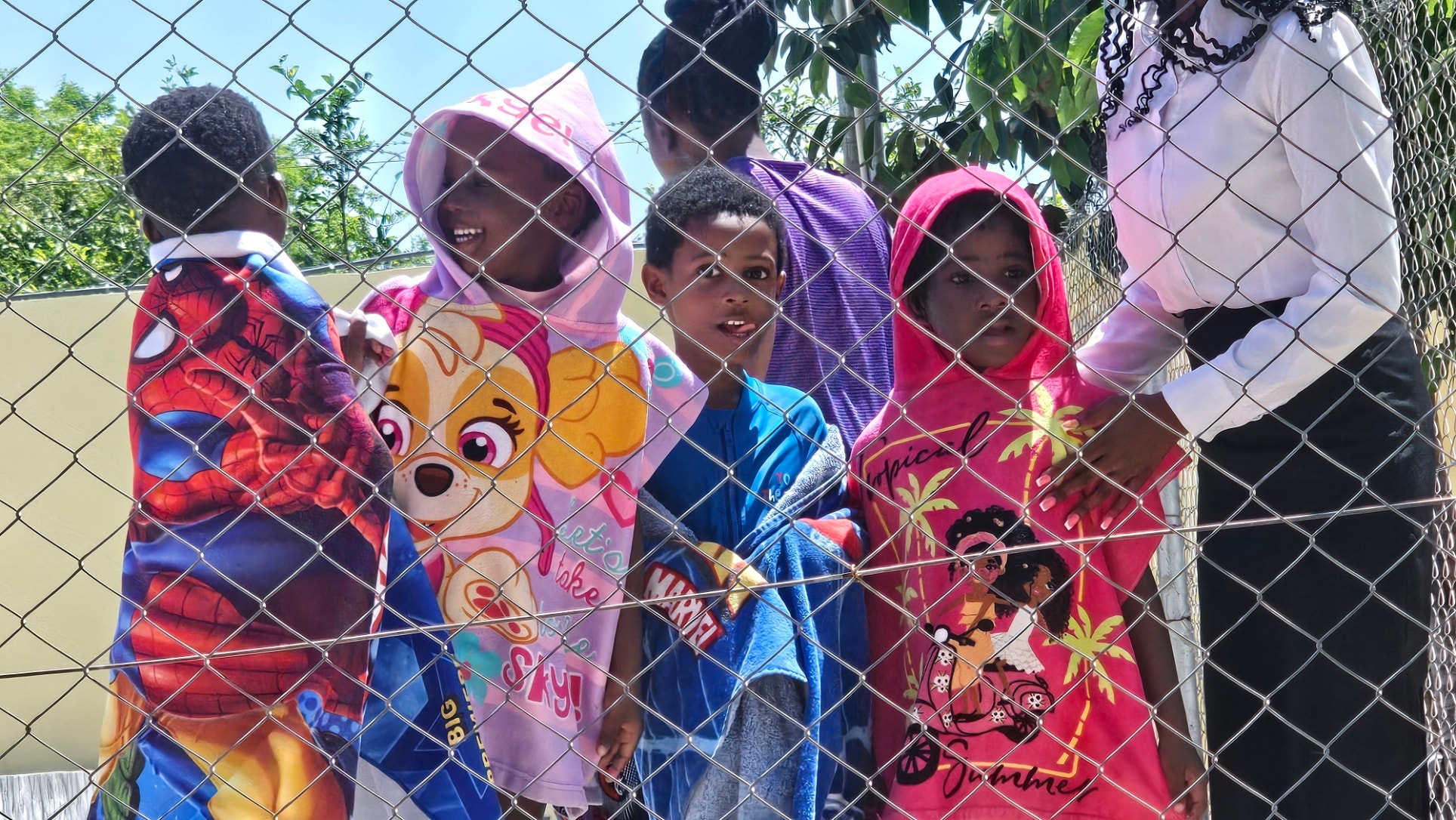 MGIS preschool children wrapped in towels at the pool fence