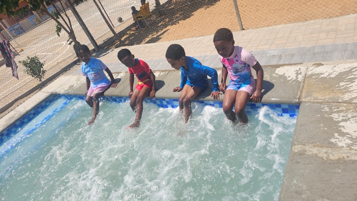 MGIS young learners sitting on the pool edge splashing water