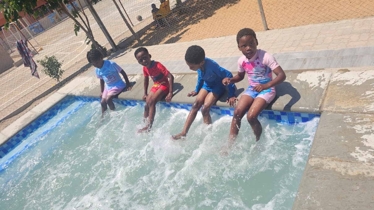 MGIS crèche children sitting on the pool edge during swimming class